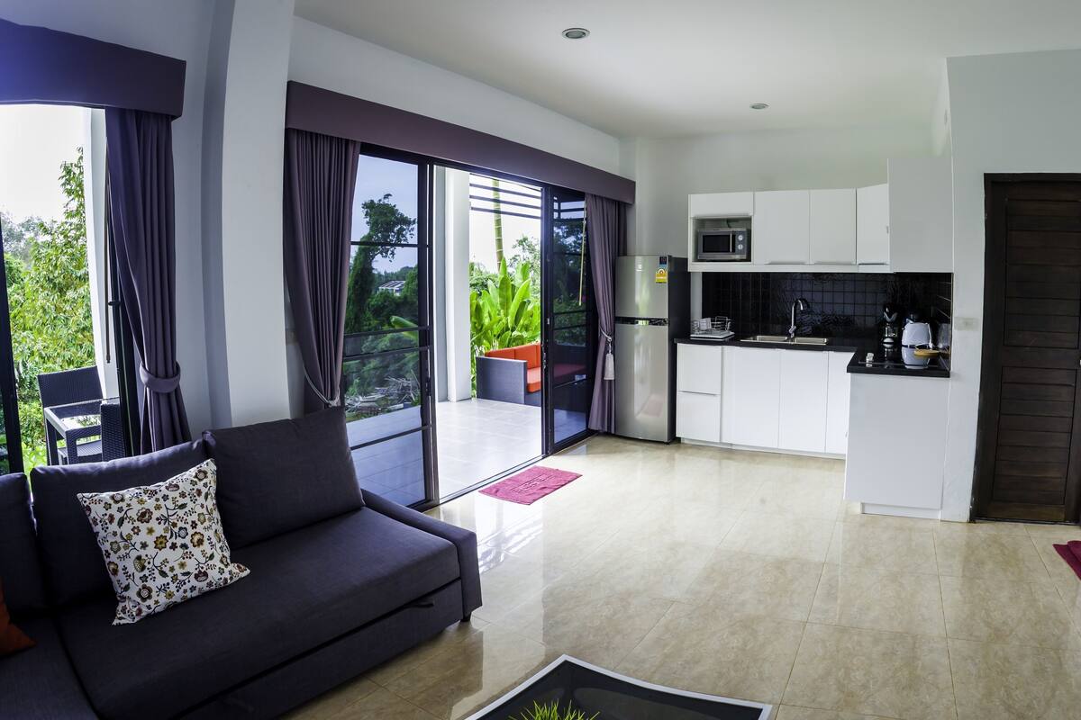 A modern living room with a sofa and a dining area with a kitchen.