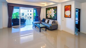 A modern living room with a sofa, a glass coffee table, and a large window with curtains.