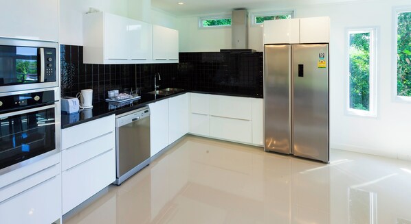 A modern kitchen with white cabinets, a black countertop, stainless steel appliances, and a dishwasher.