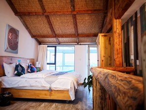 A wooden-framed bedroom with a bed, a window, and a view of the outside.