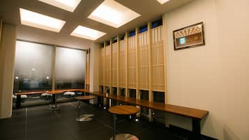 Um interior moderno com um longo banco, mesas redondas e vista através de um painel de vidro.