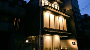 A modern building with a prominent entrance and a lit facade at dusk.