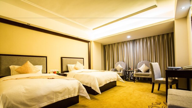 Une chambre d’hôtel avec deux lits, un bureau, une chaise et un rideau.