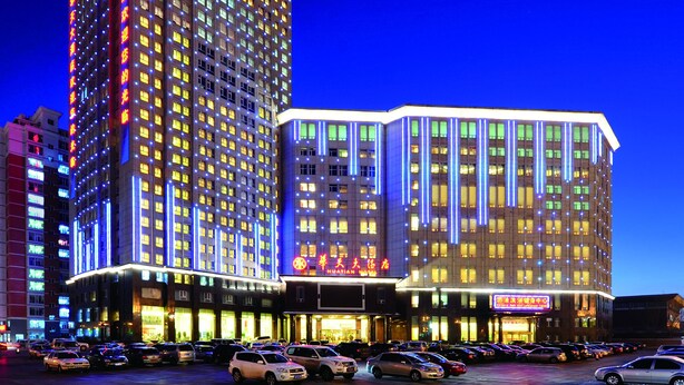 Un hotel de varios pisos con un llamativo panel de luces verticales y una sección inferior con señalización iluminada.