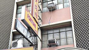 Un edificio con el letrero Fortune Hotel, una estatua y un anuncio de inscripción en un centro preescolar.