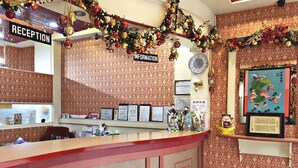 Un área de recepción con una paleta de colores rojo y beige, un reloj y varios diplomas enmarcados en la pared.