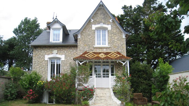 A stone house with a covered porch, a gravel pathway leading to the entrance, and a garden with various plants and flowers. - NORMAN HOUSE IN JUNO BEACH  (Bernières-Sur-Mer)