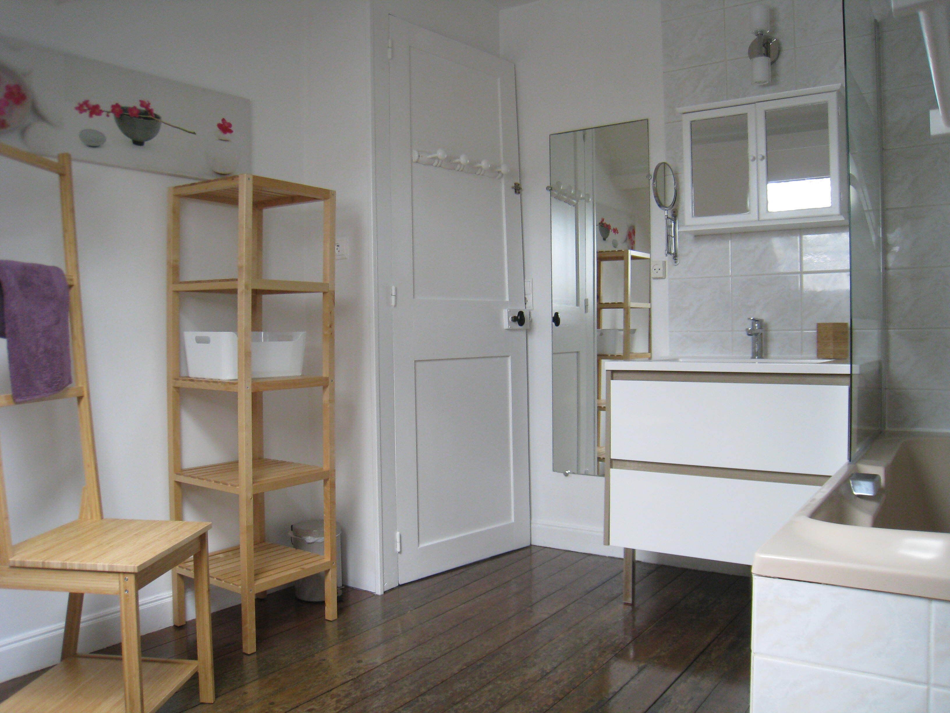 A bathroom with a wooden chair, a white sink, and a mirror.
