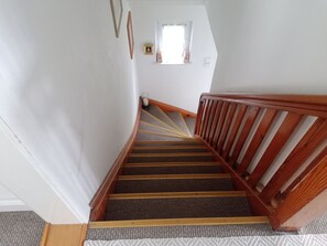 A staircase with wooden railings and carpeted steps leading to a landing.