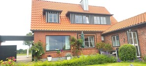 A two-story brick house with a tiled roof, large windows, and a well-maintained garden.