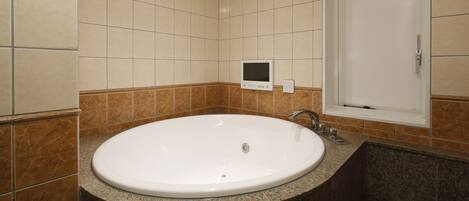 Een badkamer met een groot ovaal wastafel, een spiegel en een bedieningspaneel aan de muur.