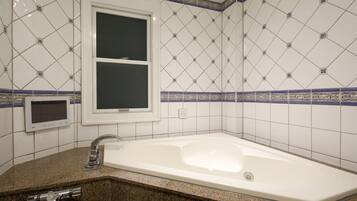 A bathroom with a white bathtub, a window, and a sink with a faucet.