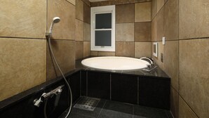 A bathroom with a bathtub, a showerhead, and a window.