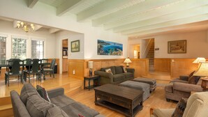 Un vaste salon comprenant un coin repas, doté de parquets en bois et d’un escalier menant à un autre niveau.
