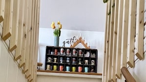 Una escalera con peldaños de madera y un estante en la parte superior que exhibe varias tazas y un florero con flores.
