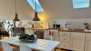Una cocina moderna con tragaluz, armarios blancos y un comedor con mesa y sillas blancas.