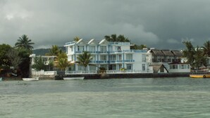 Een hotel met meerdere verdiepingen en balkons, gelegen nabij een water met boten.