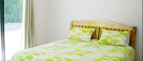 A bedroom with a wooden headboard, two pillows with a leaf pattern, and a bed with a leaf-patterned bedspread.
