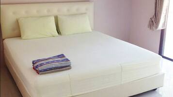 A large bed with a tufted headboard, two pillows, and a folded blanket.