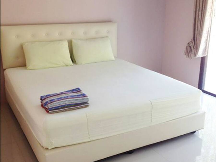 A large bed with a tufted headboard, two pillows, and a folded blanket.