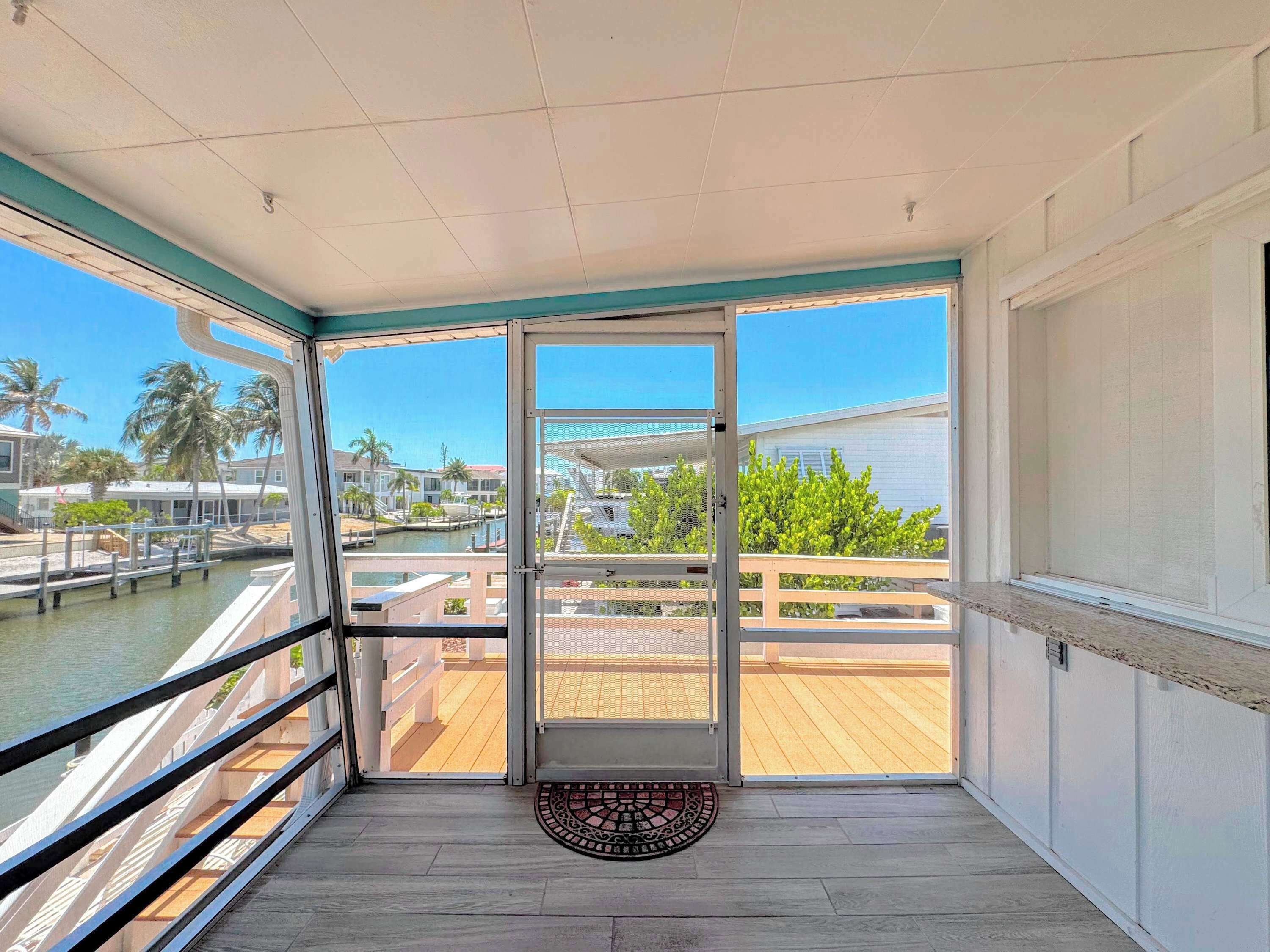 A balcony with a view of a marina, a wooden deck, and a door leading to an outdoor area.