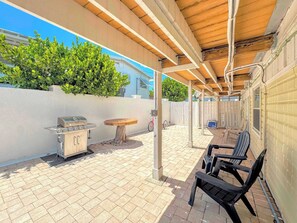 An outdoor patio with a grill, a wooden table, and black chairs. - 390 Bayland Canalfront Pool Home by Beach (Fort Myers Beach)