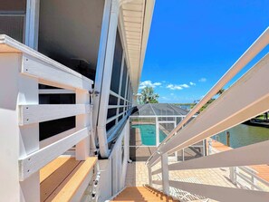 A deck with a view of a swimming pool and a clear sky. - 390 Bayland Canalfront Pool Home by Beach (Fort Myers Beach)