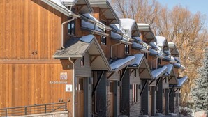 Una fila de cabañas de madera con techos inclinados y nieve en el suelo.