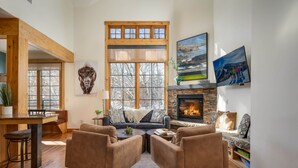 Una sala acogedora con chimenea, un ventanal grande y un comedor.