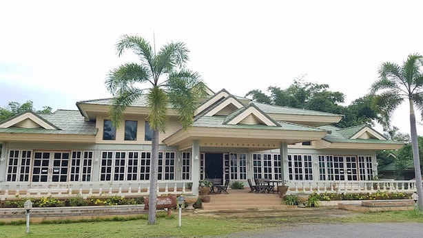 A two-story building with a covered porch, large windows, and palm trees. - Rai Fhun Pen Jing Resort (Sung Noen)