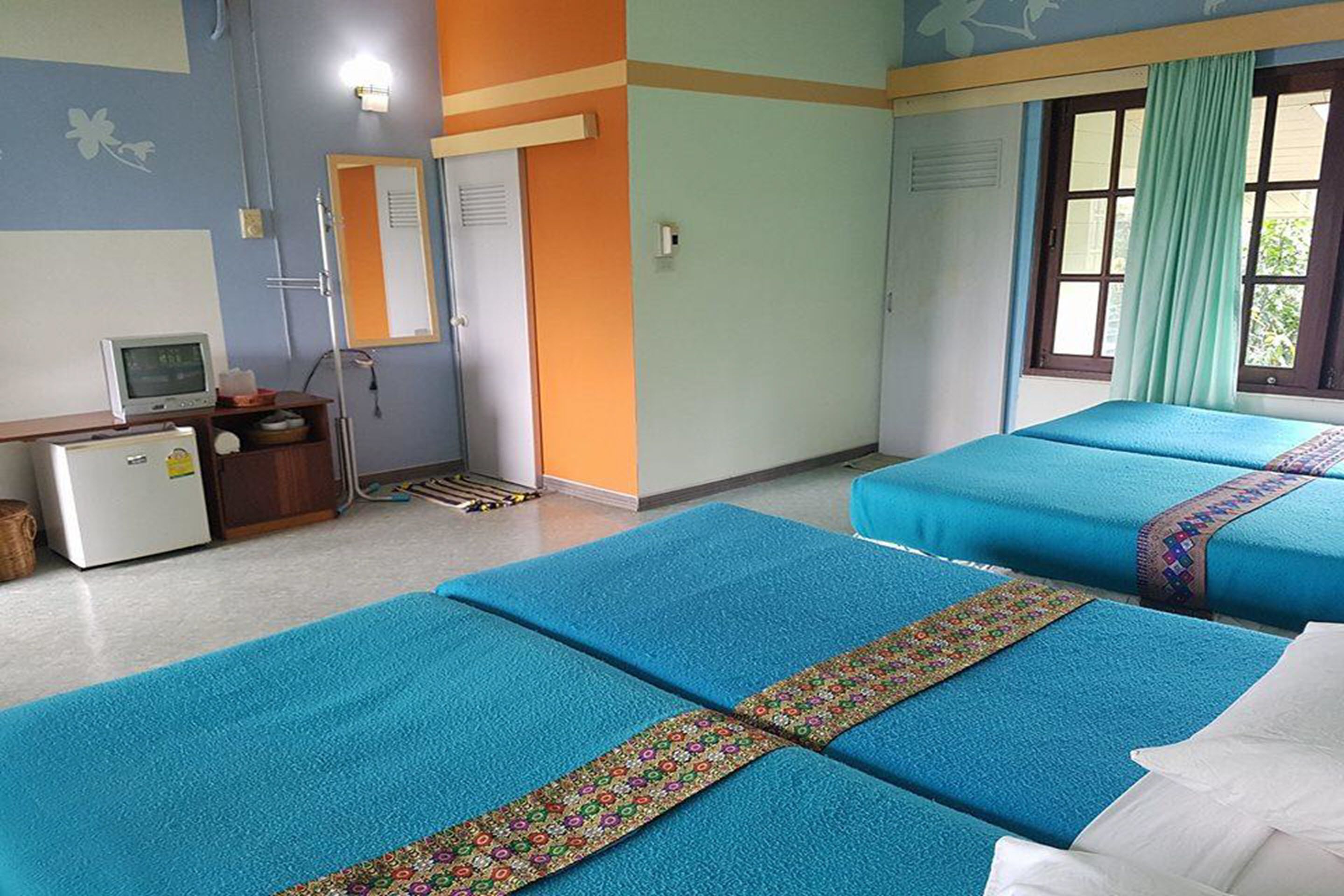 A hotel room with two beds, a desk with a computer, and a window with curtains.