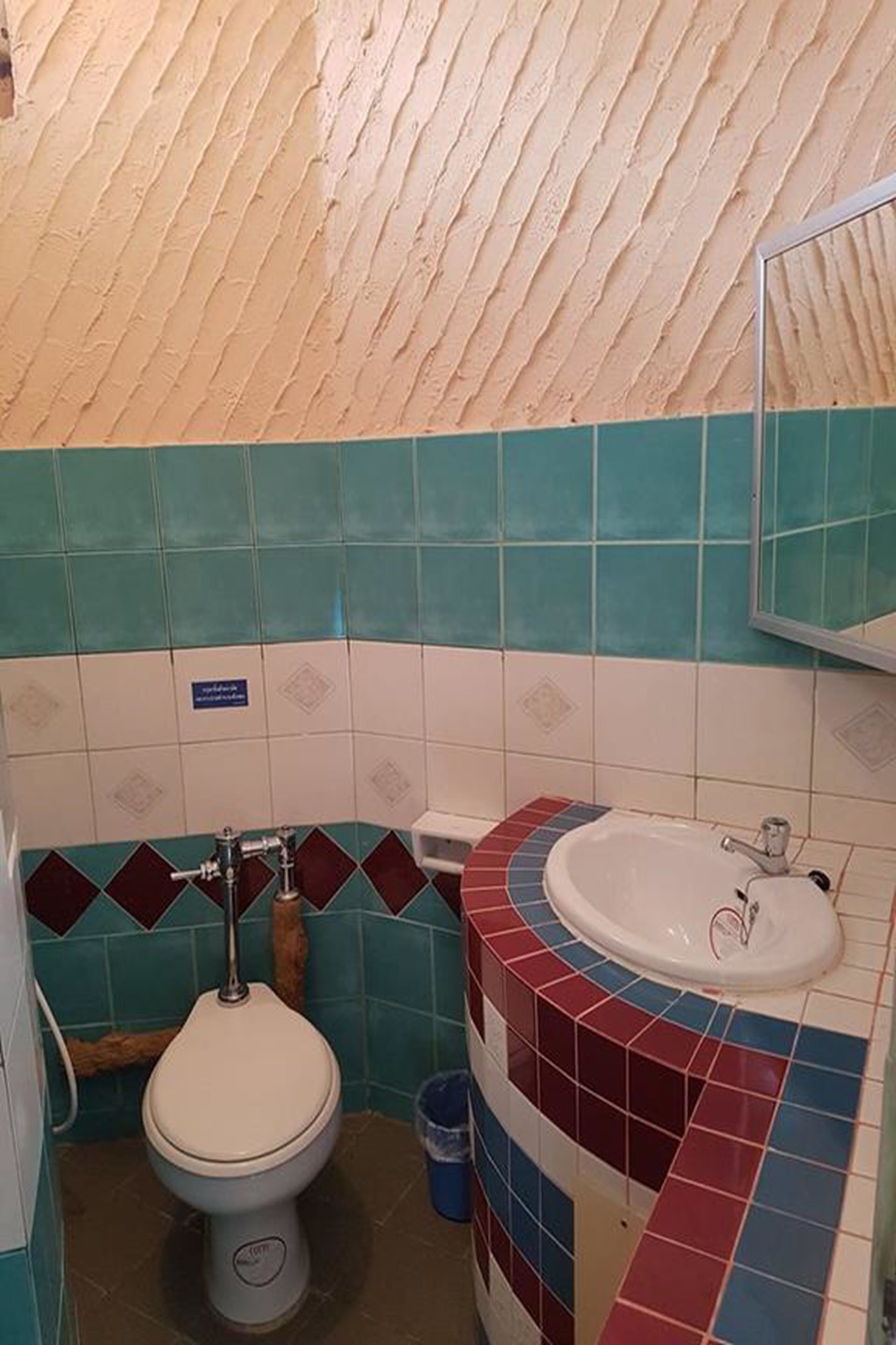A bathroom with a toilet, sink, and tiled walls.