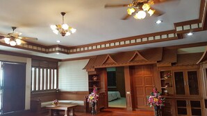 A spacious room with wooden flooring, a ceiling fan, recessed lighting, a wooden bench, and a bed with a green bedspread. - Rai Fhun Pen Jing Resort (Sung Noen)
