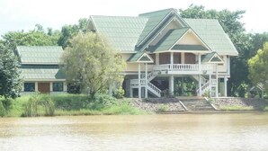 A large house with a green roof, a balcony, and a staircase leading to a porch. - Rai Fhun Pen Jing Resort (Sung Noen)