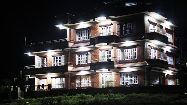 A multi-story building with balconies and illuminated windows at night. - Homestay Nepal (Kirtipur)