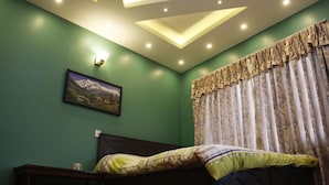 A bedroom with a bed, a nightstand, a wall-mounted light, and a framed picture. - Homestay Nepal (Kirtipur)