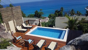 A rooftop infinity pool with lounge chairs and a wooden deck overlooking the ocean. - Kaz Bulinger (Mahé Island)