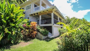 A two-story house with a covered porch and a stone staircase leading to the entrance. - Kaz Bulinger (Mahé Island)