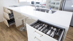 Een moderne keuken met een wit aanrecht, roestvrijstalen apparatuur en een ingebouwde lade voor keukengerei.