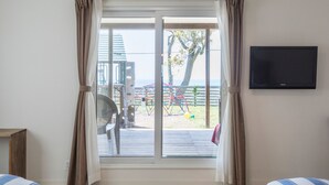 Een kamer met een grote glazen schuindeur die uitkomt op een buitengebied met een speeltuin.