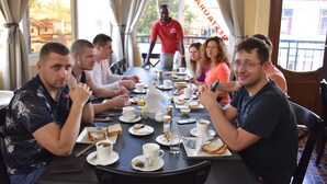 Un grupo de personas cenando en un restaurante con una mesa larga, varios platos y bebidas.