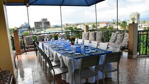 Comedor con una mesa lista para seis comensales, asientos exteriores y vistas a la ciudad.