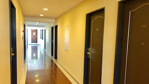 A hallway with doors on both sides, a polished wooden floor, and recessed ceiling lights. - Business Hotel Cosmo Inn (Fukuroi)