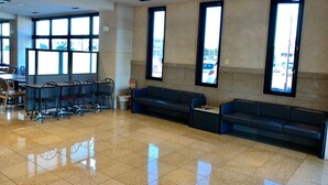 A spacious lobby with a tiled floor, large windows, and a seating area with sofas and chairs. - Business Hotel Cosmo Inn (Fukuroi)