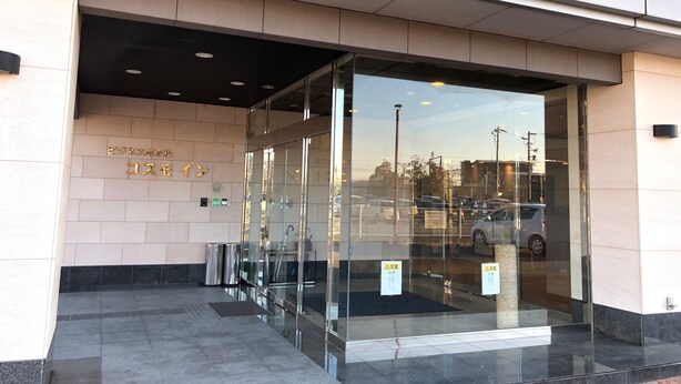A modern building entrance with glass doors, a tiled floor, and a clear view of parked cars outside. - Business Hotel Cosmo Inn (Fukuroi)