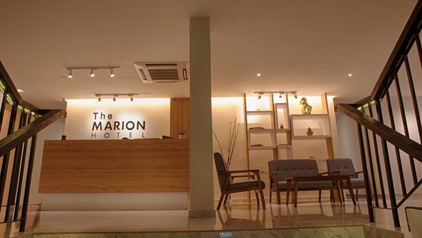 A reception area with a wooden reception desk, two chairs, and a staircase with wooden railings. - The Marion Hotel (Johor Bahru)