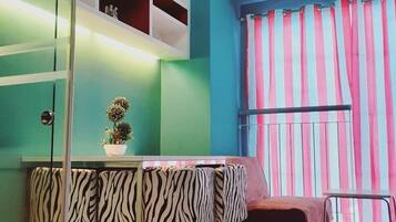 Una habitación con paredes verde agua, una mesa a rayas de cebra, una pequeña planta en maceta y una cortina a rayas.