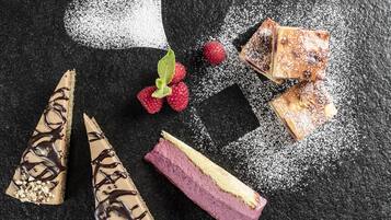 Un arreglo de postres con diversos pasteles y frutas sobre una superficie oscura.