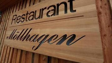 Ein hölzernes Schild mit den eingravierten Wörtern 'Restaurant' und 'Möthagen'.