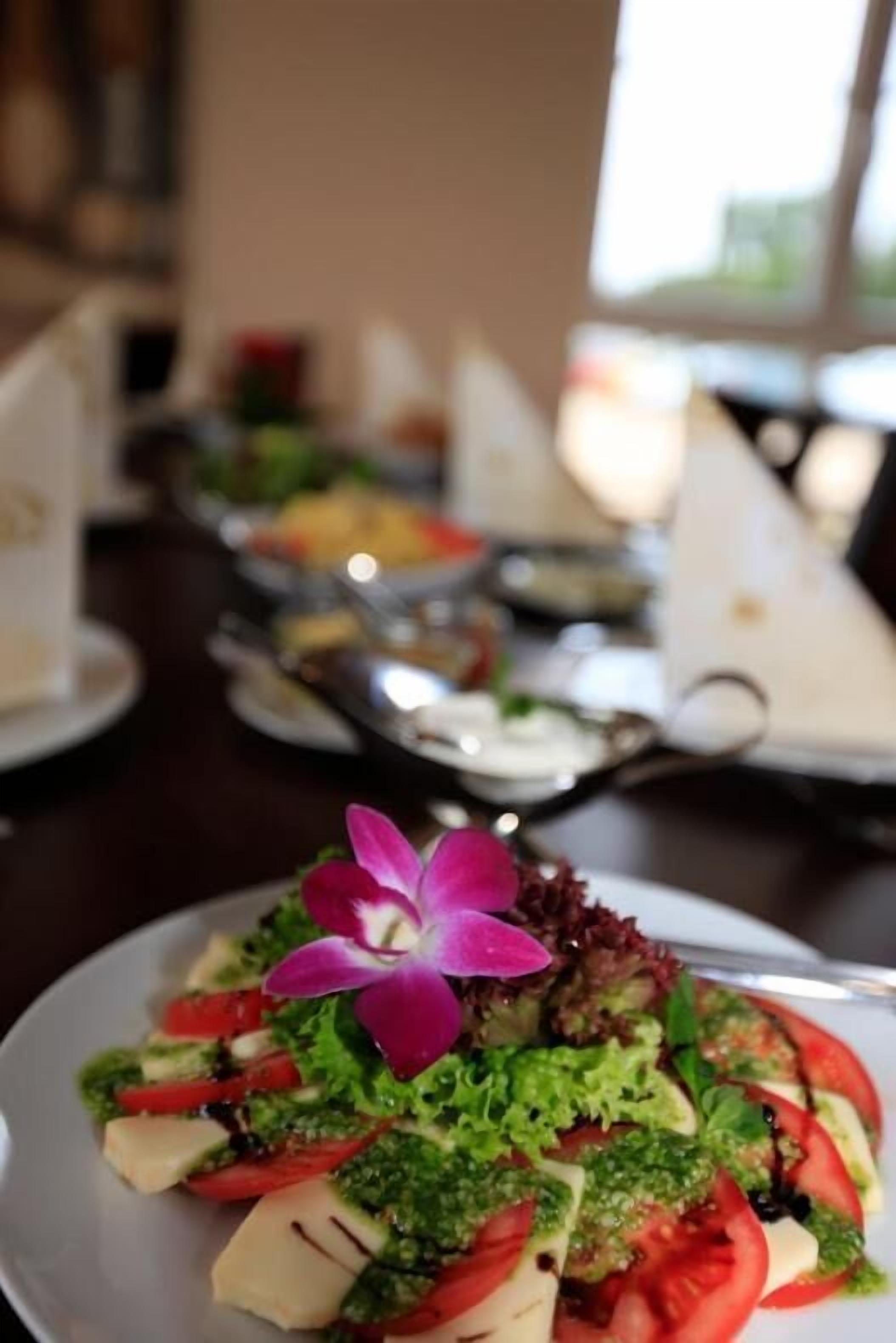 A dining table with plates of food, including a salad with a purple flower garnish.